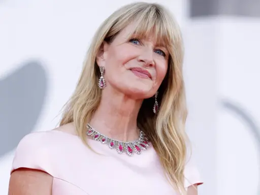 L'attrice bionda americana Laura Dern sorride con un abito rosa e gioielli scintillanti.