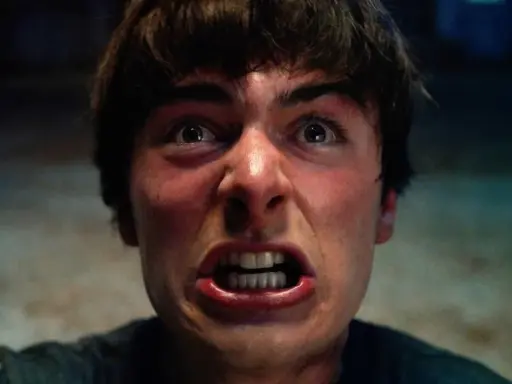 Un primo piano terrificante di un giovane con gli occhi spalancati e la bocca aperta, pronto ad affrontare le minacce di Stranger Things 5.