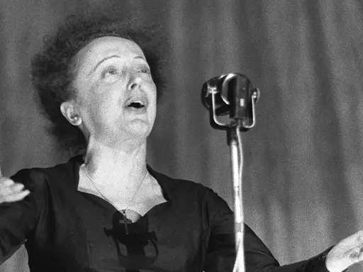 La leggendaria Édith Piaf canta con passione, la sua voce risuona mentre il pubblico immagina la sua causa morte.