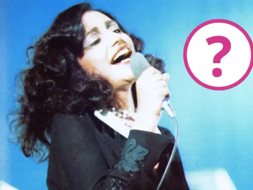 Cantante con microfono, forse un momento della sua **mia martini gravidanza**? Un punto interrogativo rosa campeggia a destra.