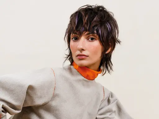 Modella con sbarazzini tagli capelli corti spettinati, ciocche viola e un look audace.