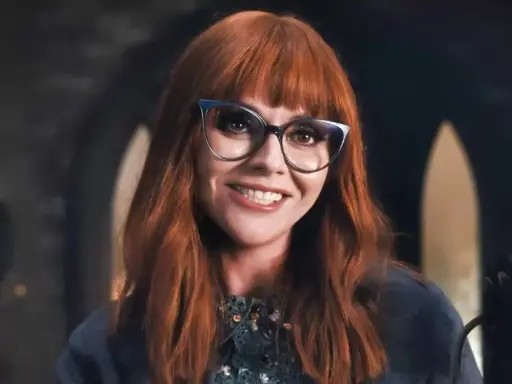 Christina Ricci, chi ha interpretato Mercoledì Addams, sorride con occhiali cat-eye e capelli rossi.