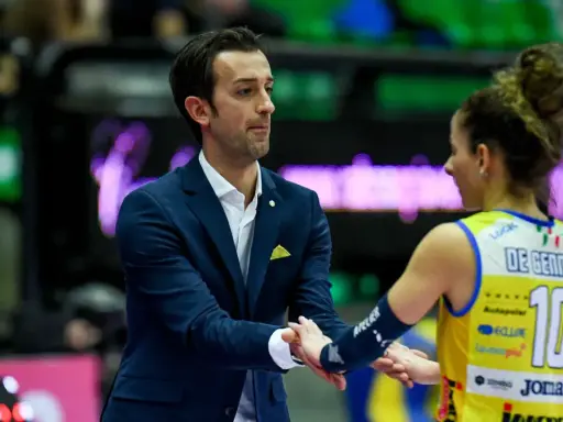 Santarelli de Gennaro, allenatore, stringe la mano a una giocatrice di pallavolo con la maglia numero 10.