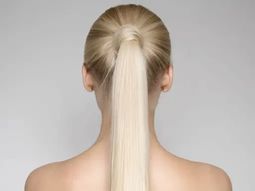 Vista posteriore di una donna con una **coda alta gonfia davanti**, capelli biondi lisci e spalle scoperte.