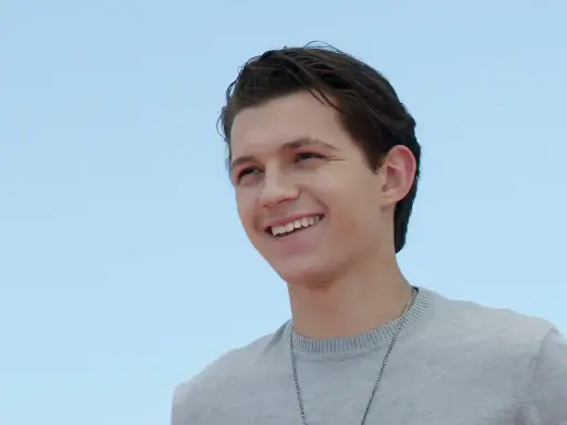 Tom Holland sorride con un maglione grigio. Chissà quanti anni ha Tom Holland?