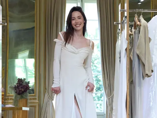 Un abito da sposa bianco, simile a quello di Michelle Hunziker con Eros Ramazzotti, indossato da una giovane donna sorridente in una stanza elegante.