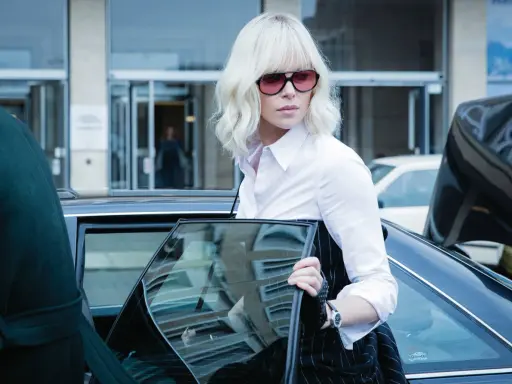 Annalisa, la protagonista di Atomic Blonde, scende da un'auto con un look audace e un'aria determinata.