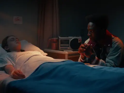 Lucas veglia su Max, addormentata in ospedale. Una cassetta e un disegno infantile sul muro ricordano i tempi felici di Stranger Things.