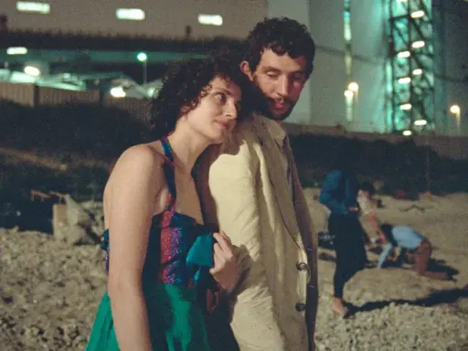 Il cast de "La Chimera" in un momento intimo, con altre figure sfocate sullo sfondo notturno.