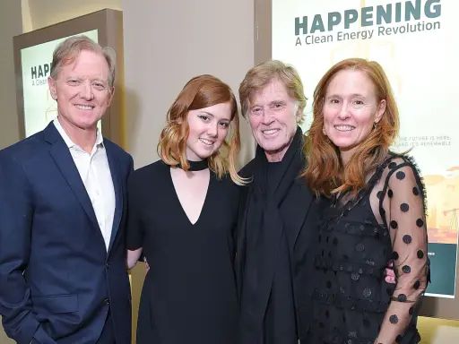 Robert Redford con i suoi figli, un momento di famiglia davanti a un poster su un'energia pulita.