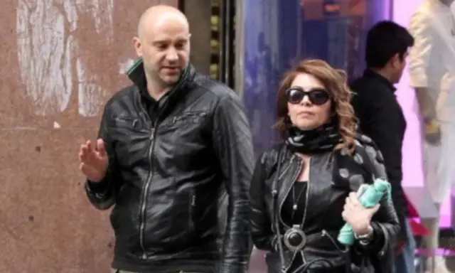 Cristina D'Avena passeggia con quello che sembra essere il suo marito, entrambi vestiti di pelle nera.