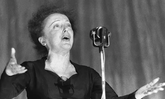 La leggendaria Édith Piaf canta con passione, la sua voce risuona mentre il pubblico immagina la sua causa morte.