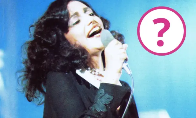 Cantante con microfono, forse un momento della sua **mia martini gravidanza**? Un punto interrogativo rosa campeggia a destra.