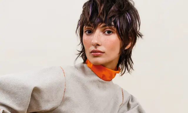 Modella con sbarazzini tagli capelli corti spettinati, ciocche viola e un look audace.