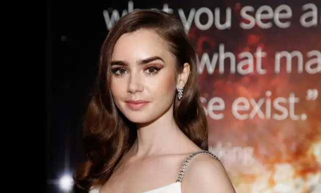 Lily Collins, protagonista di film e programmi TV, con un'espressione pensierosa e un abito scintillante.