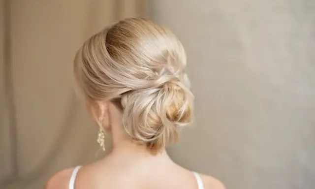 Chignon basso cerimonia con capelli biondi intrecciati, un'acconciatura elegante e raffinata per un'occasione speciale.