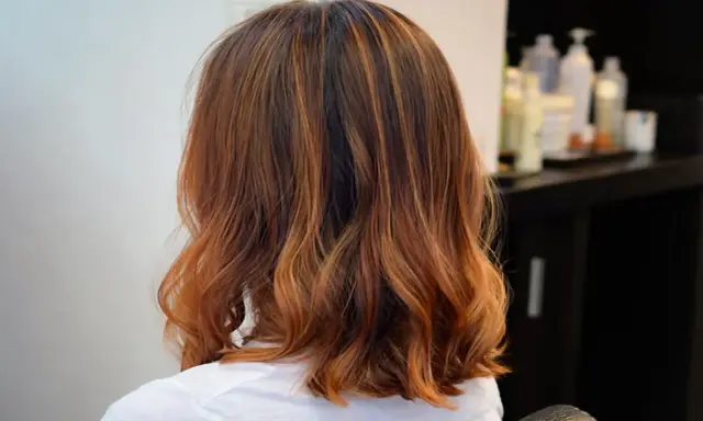 Capelli castani con riflessi ramati, un taglio di capelli un po più lungo del caschetto, leggermente mossi.