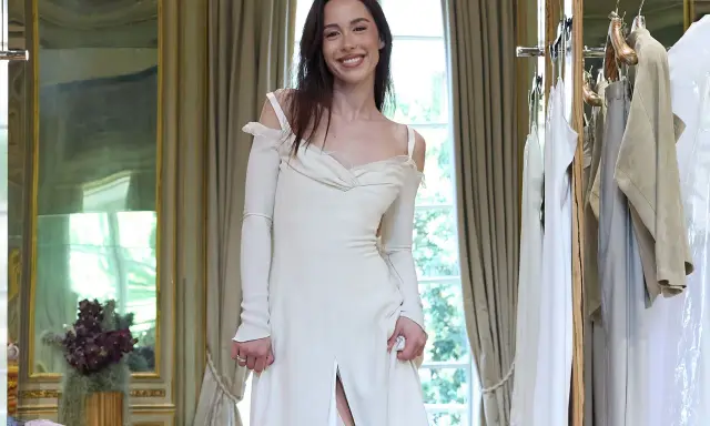 Un abito da sposa bianco, simile a quello di Michelle Hunziker con Eros Ramazzotti, indossato da una giovane donna sorridente in una stanza elegante.