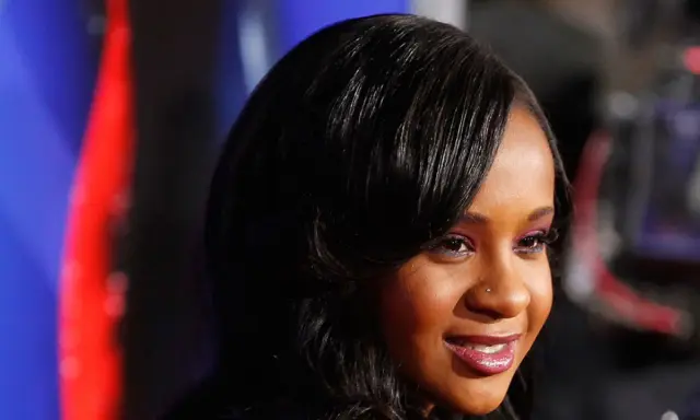 La figlia di Whitney Houston, Bobbi Kristina Brown, sorride con un trucco viola e capelli scuri.
