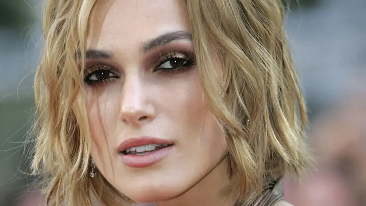 Primo piano di una donna con taglio butterfly capelli corti biondi, trucco occhi intenso e labbra rosa.