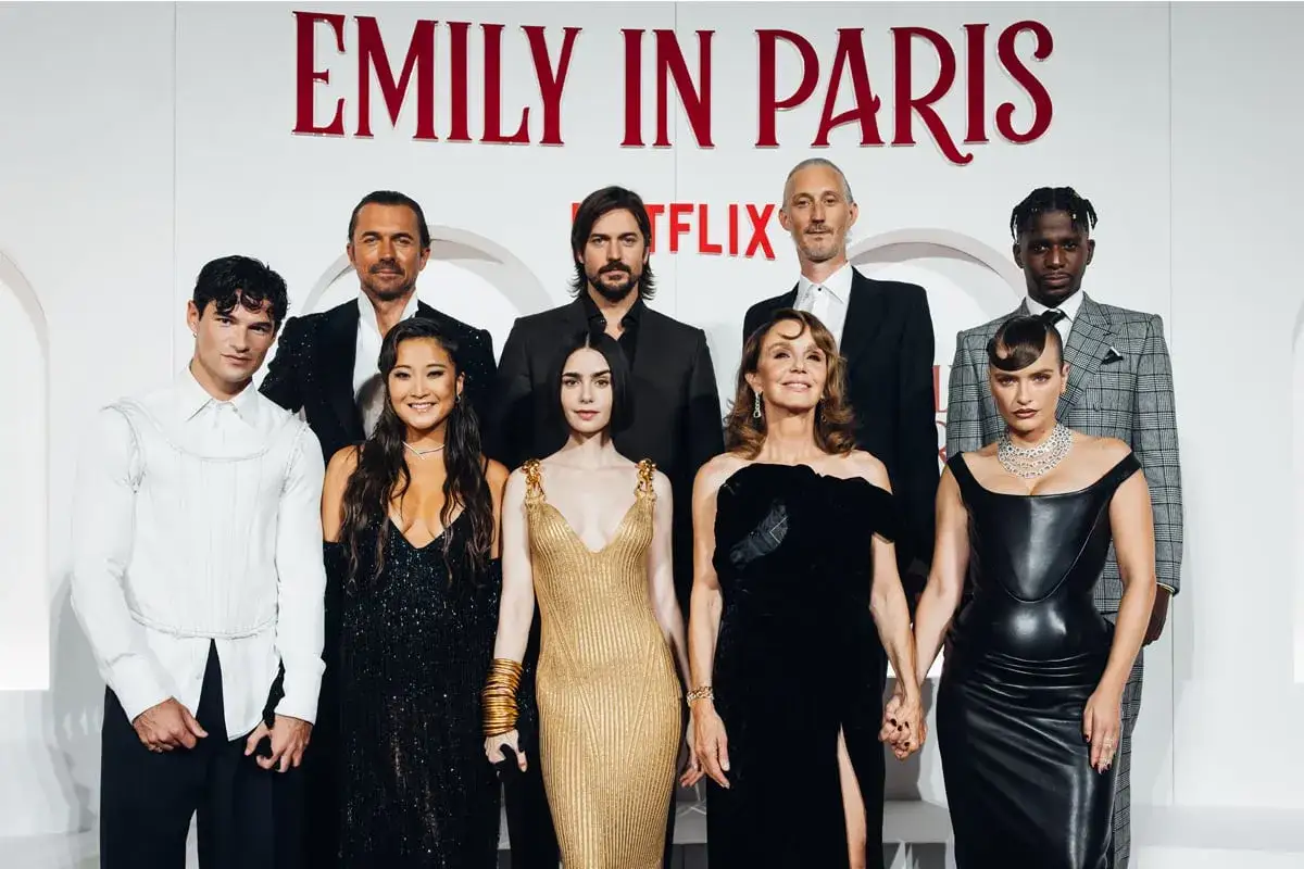 Il cast di Emily in Paris 4 posa sorridente. Lily Collins, in oro, brilla accanto ai suoi colleghi.