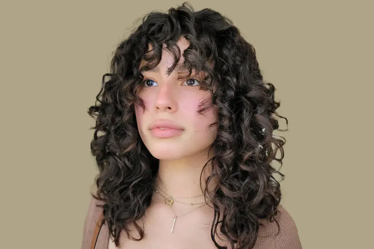 Ragazza con splendidi capelli ricci naturali con frangia, che incorniciano il viso con morbidezza.