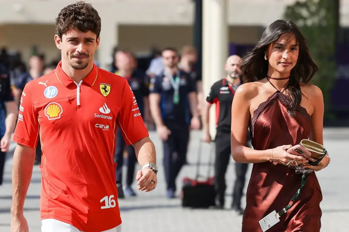 Charles Leclerc e la sua fidanzata passeggiano, lui con la divisa Ferrari, lei con un abito elegante.