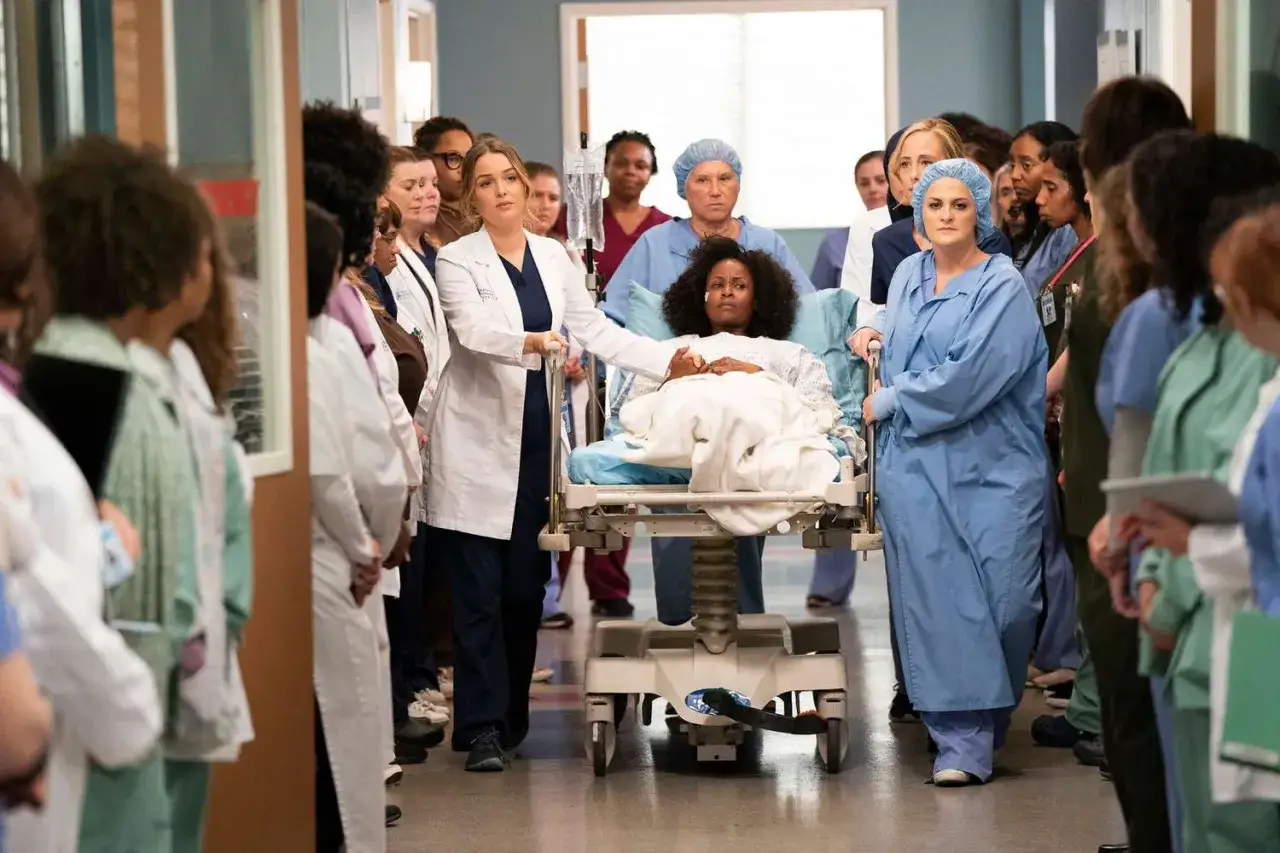 Un'ambulanza trasporta una paziente, circondata da medici e infermieri, in una scena di Grey's Anatomy 22.