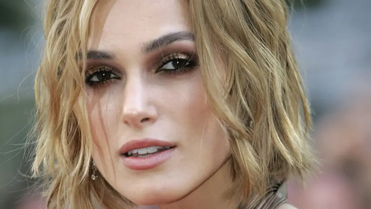 Primo piano di una donna con un taglio butterfly capelli corti biondi e un trucco occhi intenso.