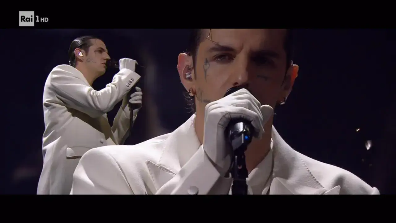 Achille Lauro, con guanti bianchi e un completo elegante, canta perdutamente sul palco.
