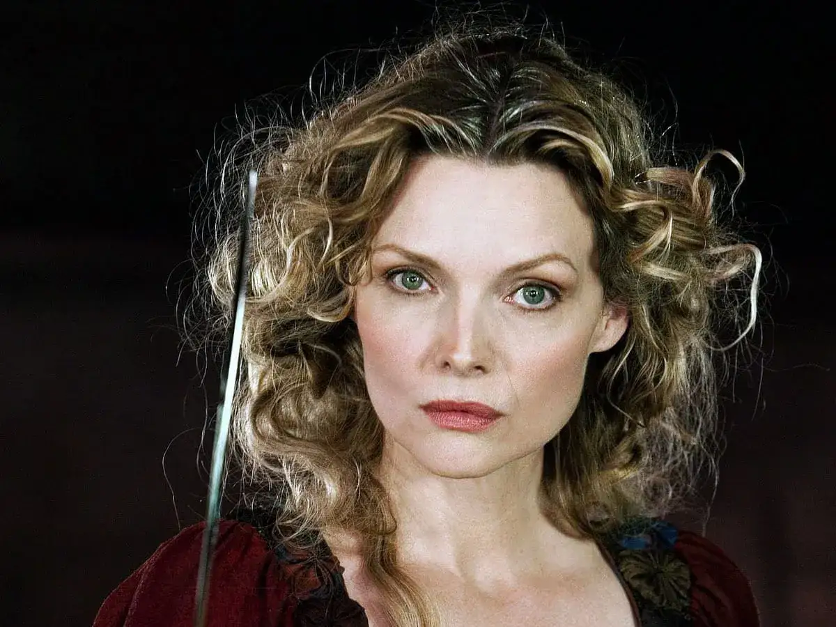 Michelle Pfeiffer con capelli ricci e sguardo intenso, forse in un film d'epoca.