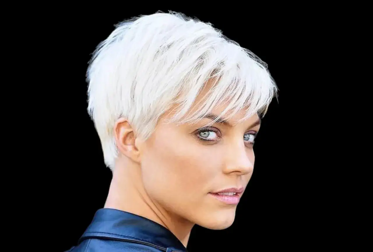 Donna con capelli biondo platino, tagli cortissimi rasato pixie cut corto, sguardo intenso e giacca di pelle.