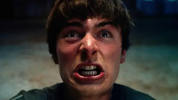 Un primo piano terrificante di un giovane con gli occhi spalancati e la bocca aperta, pronto ad affrontare le minacce di Stranger Things 5.