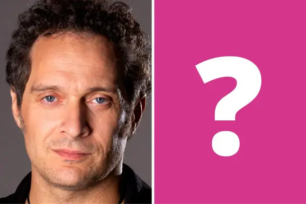 Primo piano di Claudio Santamaria, con un punto interrogativo rosa a destra. Forse si cerca la sua ex moglie?