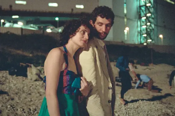 Il cast de "La Chimera" in un momento intimo, con altre figure sfocate sullo sfondo notturno.