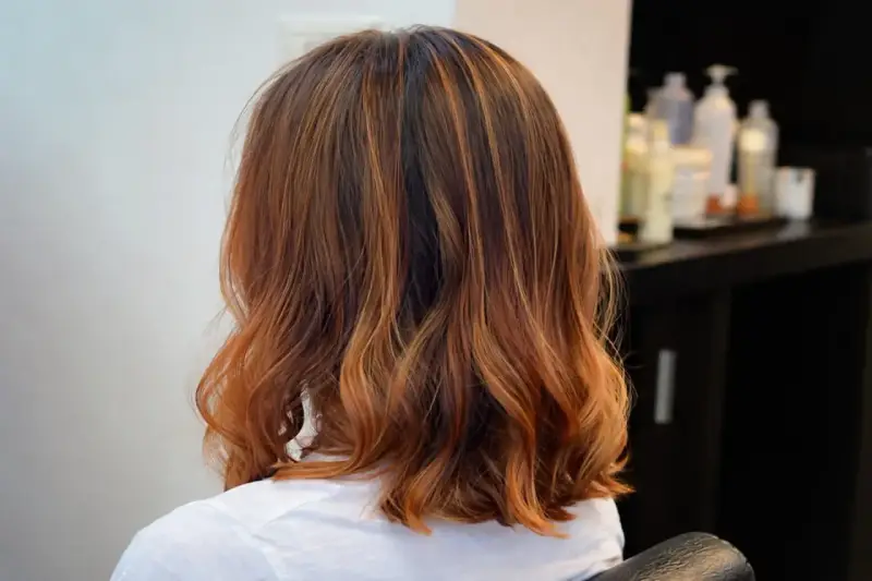 Capelli castani con riflessi ramati, un taglio di capelli un po più lungo del caschetto, leggermente mossi.